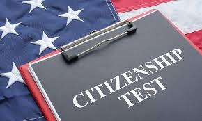 Photograph of the U.S. flag, with a clipboard laying on it that has a stack of paperwork that says "CITIZENSHIP TEST"