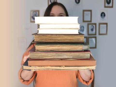 person holding stack of old books