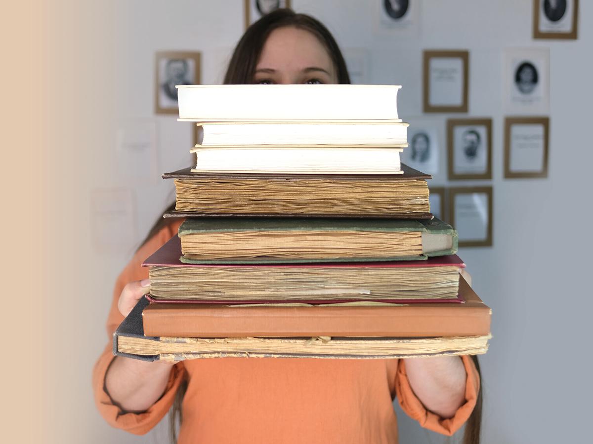 person holding stack of old books